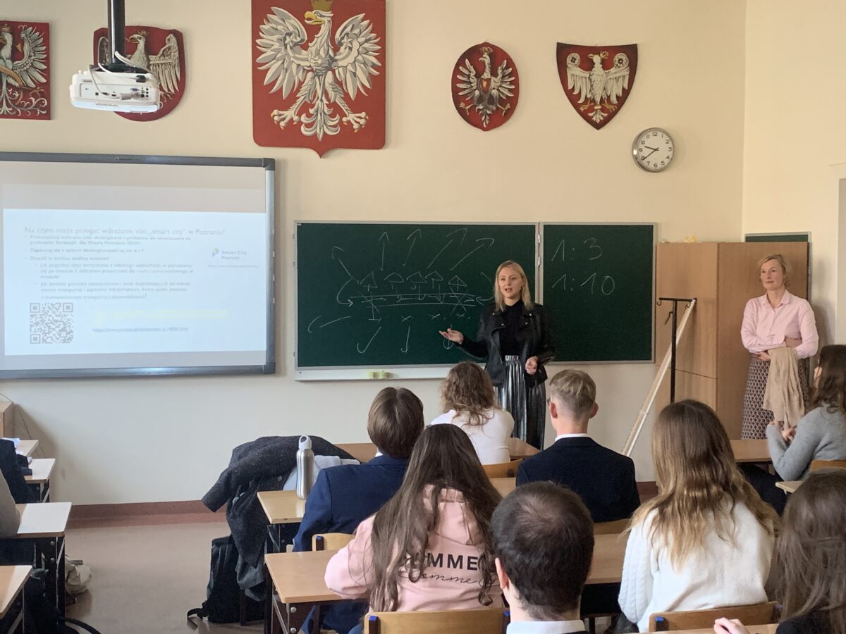 Olga Dzieciątkowska prowadzi lekcję w II LO w Poznaniu, w tle tablica i prezentacja