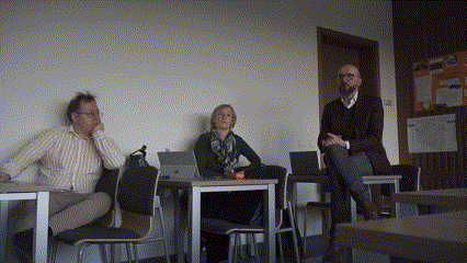 dr Malaga, prof. Klafkowska oraz student - siedzą w sali, dr Malaga siedzi na krześle i tłumaczy gestykulując