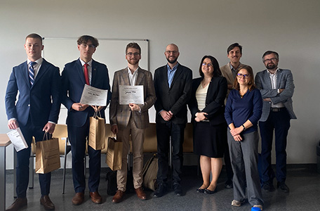 Grupa ludzi stoi przed białą tablicą i uśmiecha się